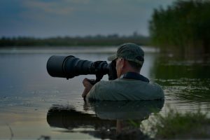 a photographer is chest deep in a lake holding a camera