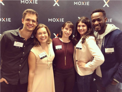 A group poses in front of a Moxie background